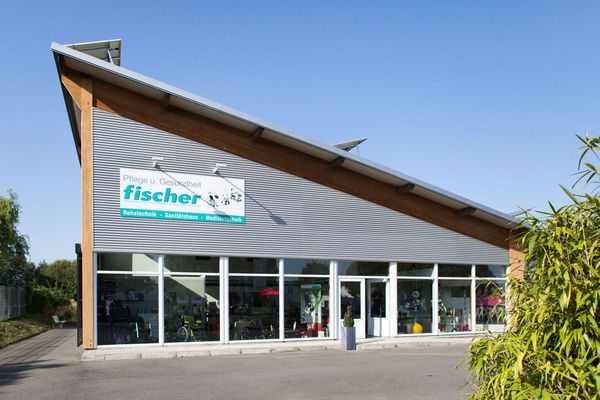 Geschäftsbau der Pflege und Gesundheit Fischer Heller, moderner Geschäftsbau der Firma Pflege und Gesundheit Fischer mit Schrägdach, Fensterfront und Logo.